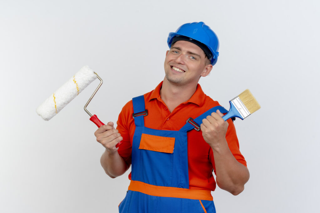 smiling-young-male-builder-wearing-uniform-safety-helmet-holding-paint-roller-with-paint-brush-white (1)